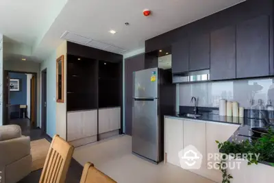 Modern kitchen with sleek cabinets and stainless steel fridge in open-plan apartment