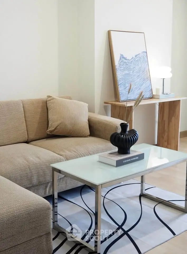 Stylish living room with modern decor, beige sofa, glass coffee table, and artistic wall art.