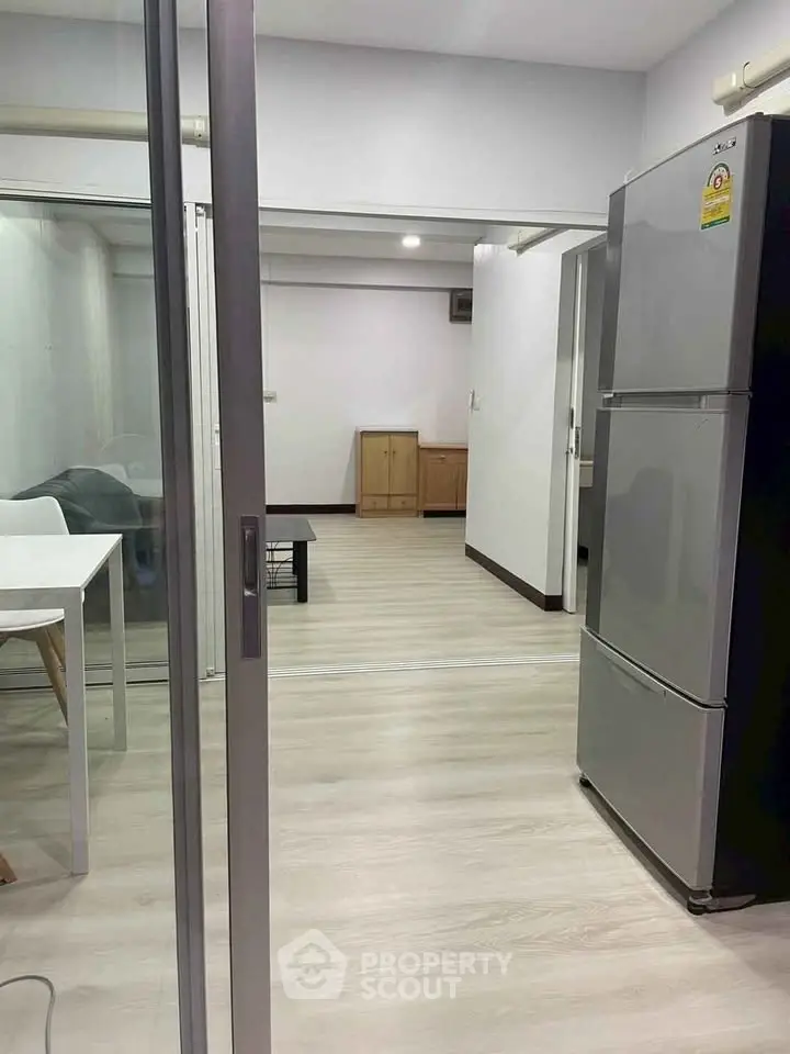 Modern apartment interior with sleek kitchen and spacious living area, featuring a large fridge and stylish decor.