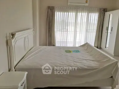 Spacious bedroom with large window and elegant white furniture, perfect for serene living.