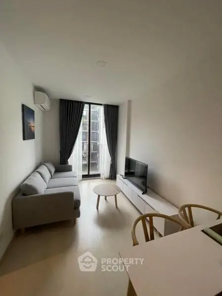 Modern living room with sleek furniture and large window offering natural light.
