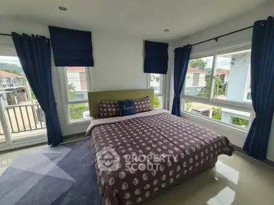 Spacious bedroom with large windows and modern decor in a bright, airy home.