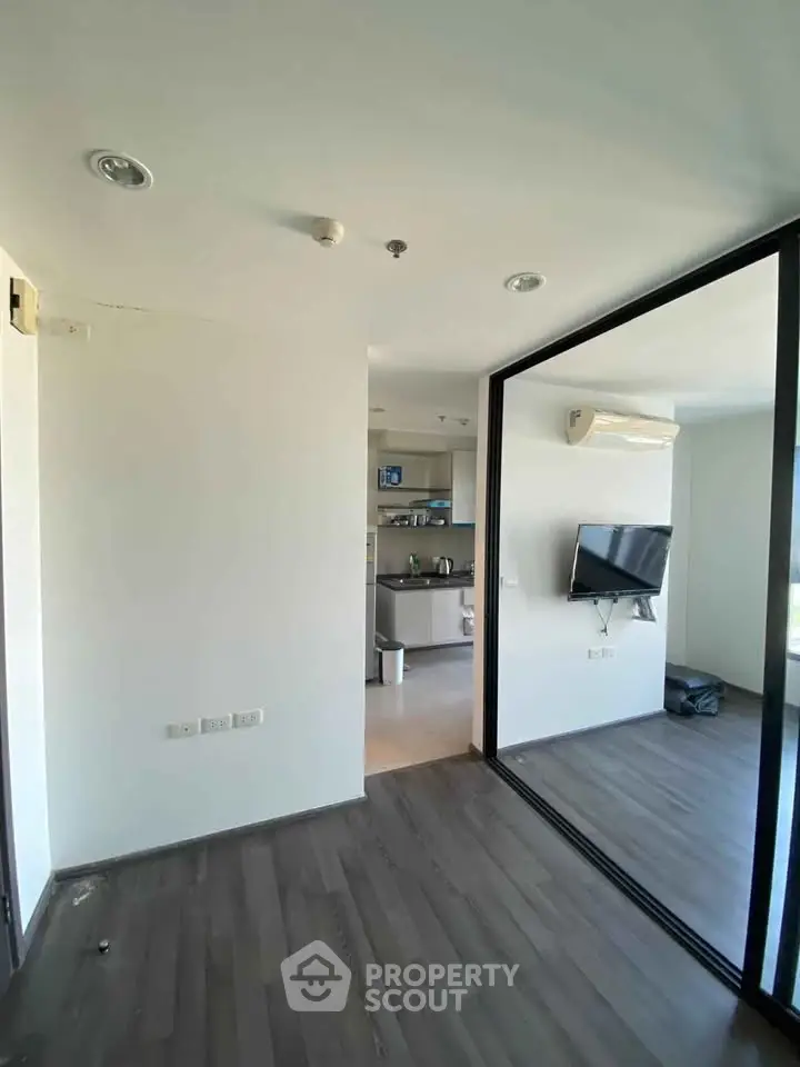 Modern apartment interior with sleek design and open layout, featuring a wall-mounted TV and stylish flooring.