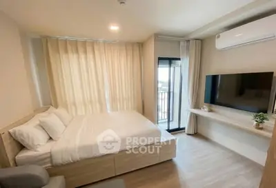 Modern bedroom with large window and wall-mounted TV, featuring minimalist decor and natural light.