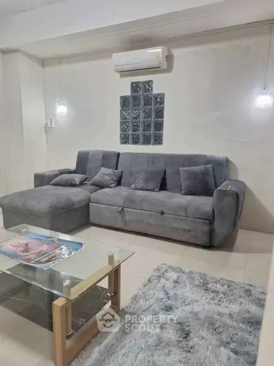 Modern living room with plush gray sofa and stylish glass coffee table