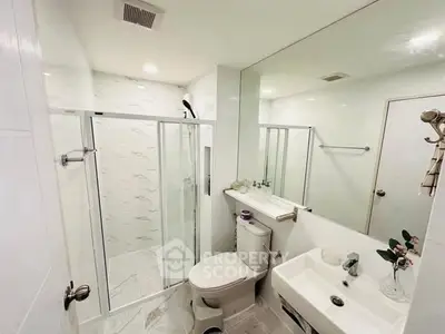 Modern bathroom with glass shower and sleek fixtures in a bright, minimalist design.