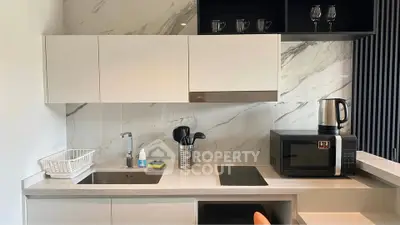 Modern kitchen with sleek cabinetry, marble backsplash, and built-in appliances including microwave and electric stove.