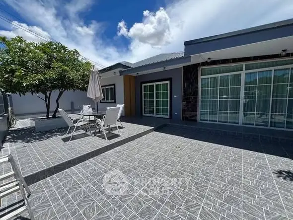Modern home exterior with spacious patio and outdoor seating area under clear blue sky.