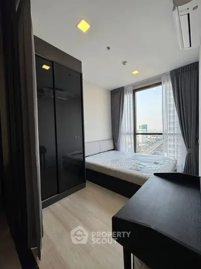 Modern bedroom with city view, featuring sleek black wardrobe and large window.