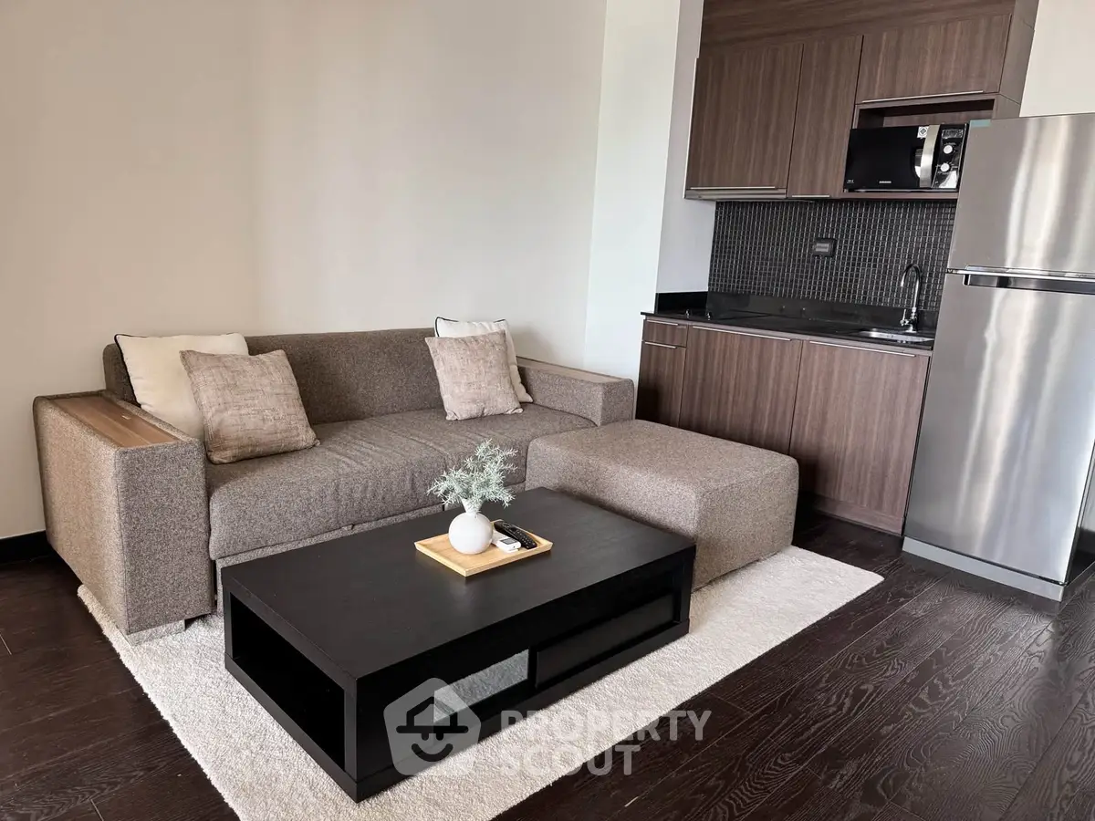 Modern living room with sleek kitchenette and stylish furniture in a cozy apartment.