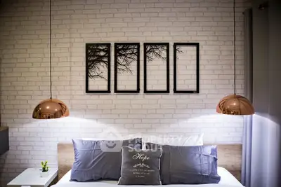 Modern bedroom with stylish decor and ambient lighting, featuring a cozy bed and artistic wall frames.