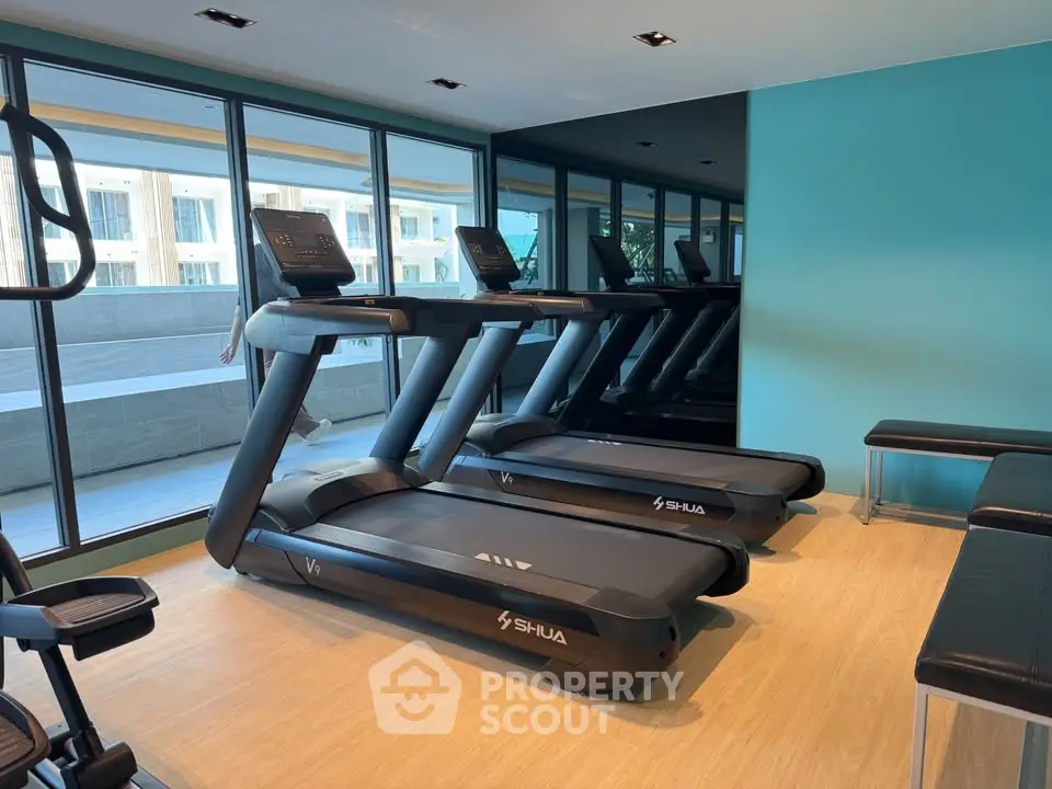 Modern gym with treadmills and large windows in a luxury apartment building.