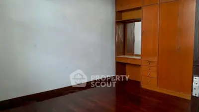 Spacious empty room with wooden built-in wardrobe and polished floor
