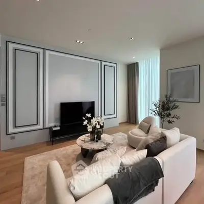 Elegant living room with modern decor and large TV, featuring a cozy white sofa and stylish coffee table.