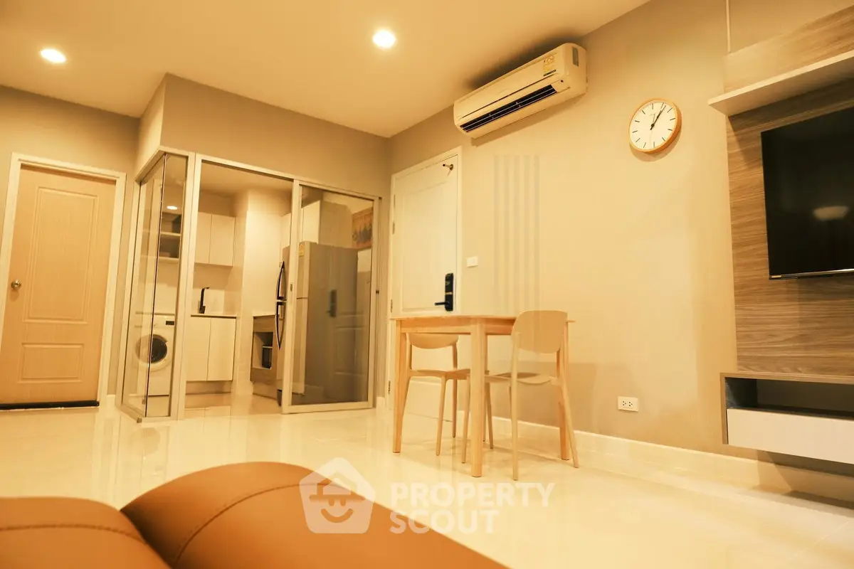 Modern living room with open kitchen, featuring sleek appliances and stylish decor.