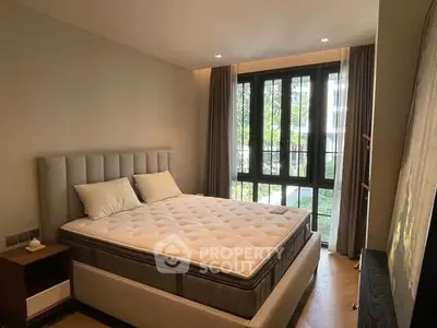 Cozy bedroom with large window and modern decor, perfect for relaxation.