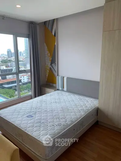 Modern bedroom with city view, featuring a comfortable bed and stylish decor in a high-rise apartment.