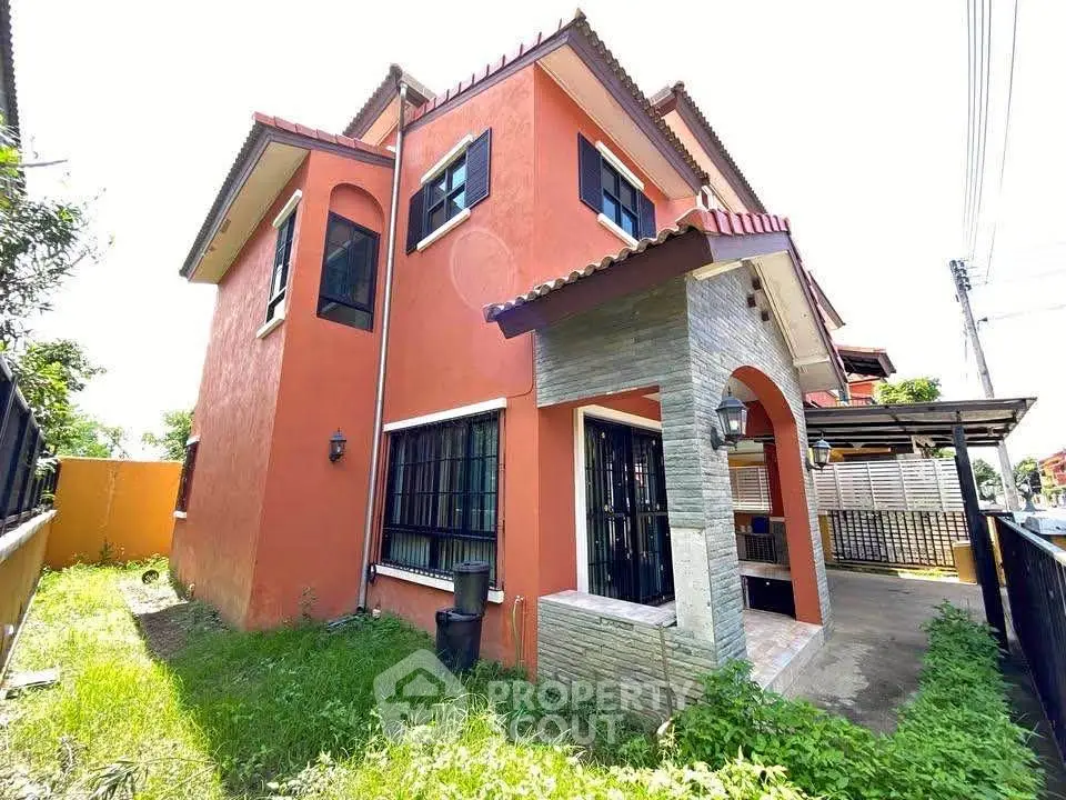Charming two-story house with red exterior and lush green yard, perfect for family living.