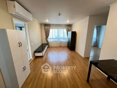 Spacious living room with wooden flooring and modern furnishings in a bright apartment.