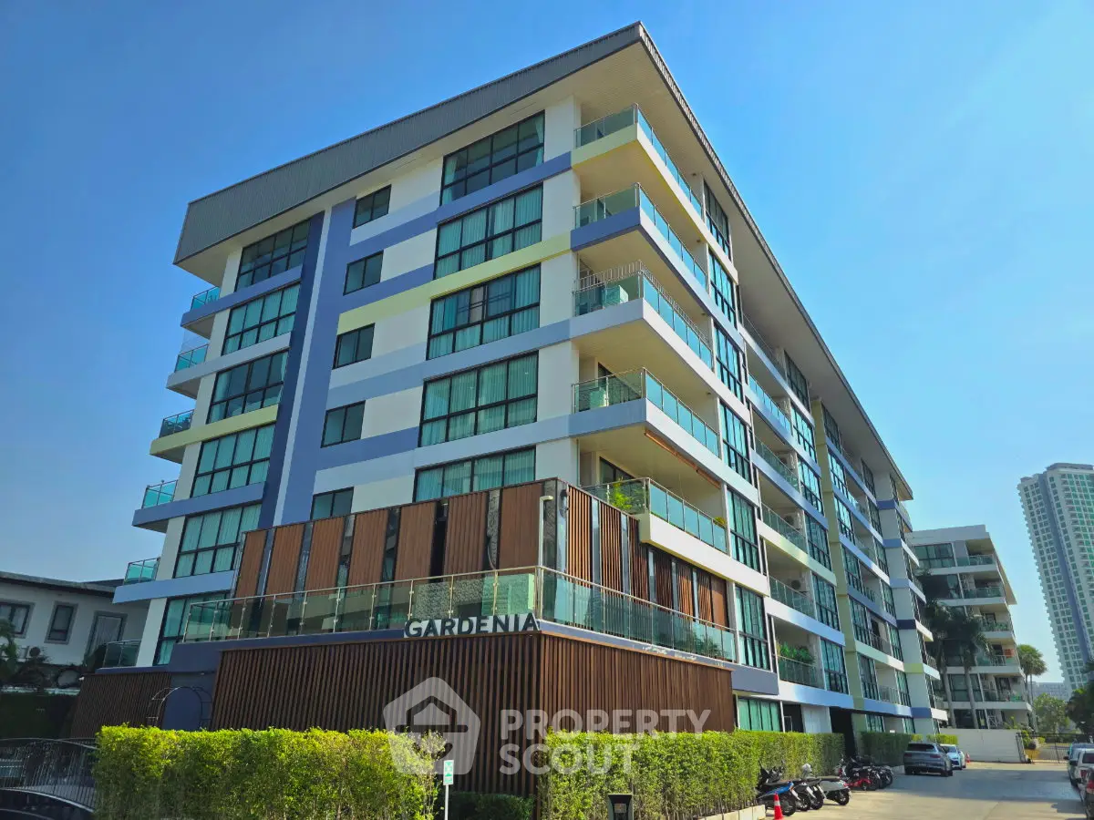 Modern multi-story residential building with glass balconies and lush greenery, perfect for urban living.
