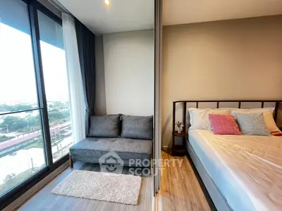 Modern bedroom with large windows and cozy seating area, offering a stunning city view.