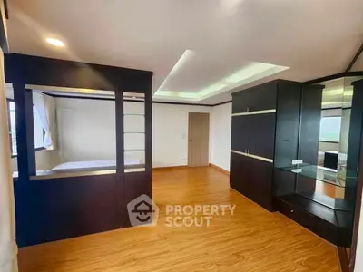 Spacious modern bedroom with wooden flooring and built-in storage solutions.