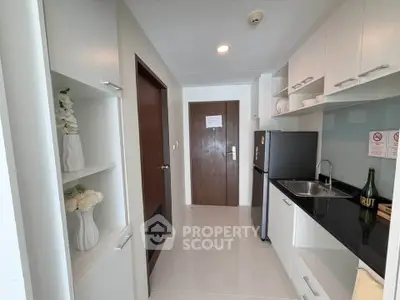 Modern kitchen with sleek cabinets and stainless steel fridge in compact layout.