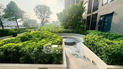 Luxurious garden area with lush greenery and modern seating in upscale residential complex.