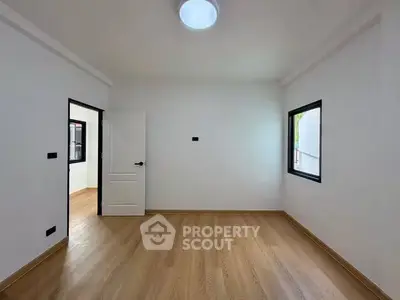 Spacious empty room with wooden flooring and bright natural light, ideal for customization.