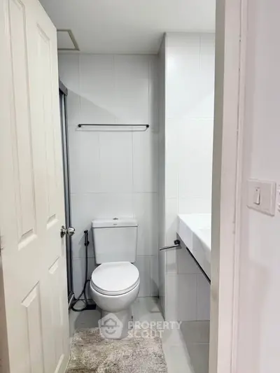 Modern bathroom with sleek design and white tiles, featuring a toilet and sink.