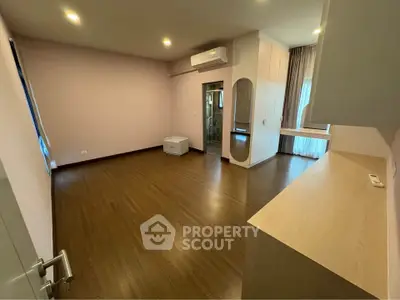 Spacious bedroom with wooden flooring and modern air conditioning unit