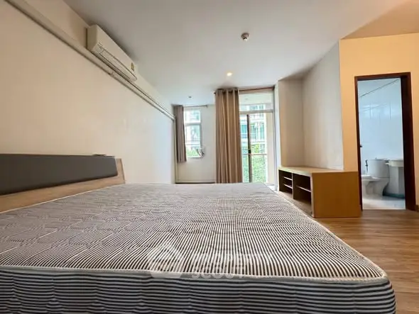 Spacious bedroom with large window and ensuite bathroom in modern apartment.