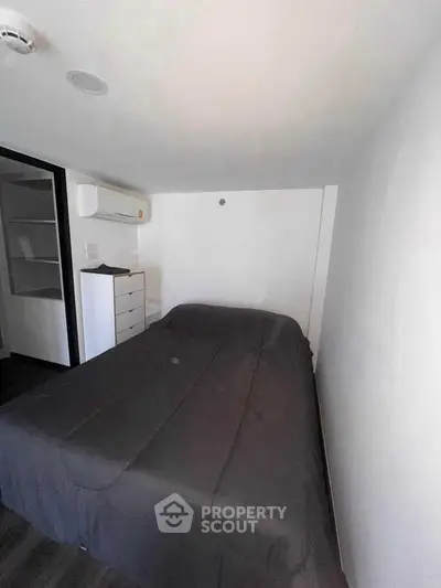 Cozy minimalist bedroom with modern air conditioning and sleek black bedding.