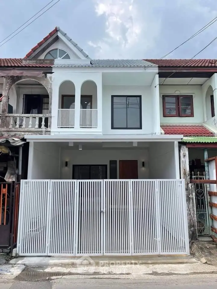 Charming two-story townhouse with modern facade and gated entrance in a suburban neighborhood.