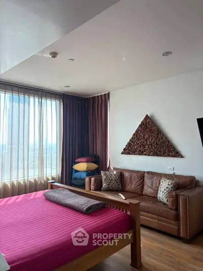 Stylish bedroom with leather sofa and large window offering city views