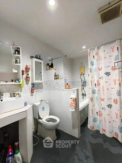 Cozy bathroom with modern fixtures and playful shower curtain, ideal for compact living spaces.