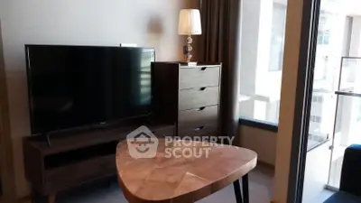 Modern living room with sleek TV, stylish wooden furniture, and large windows for natural light.