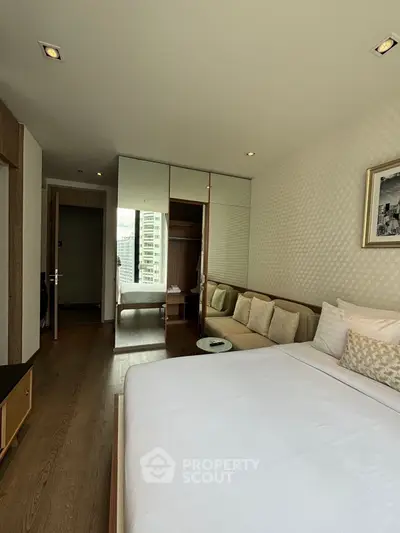 Modern bedroom with city view, featuring elegant decor and cozy seating area.