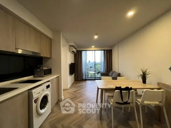 Modern open-plan living room with kitchen and balcony view