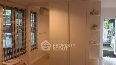 Bright interior with large windows and modern closet, overlooking a lush garden.