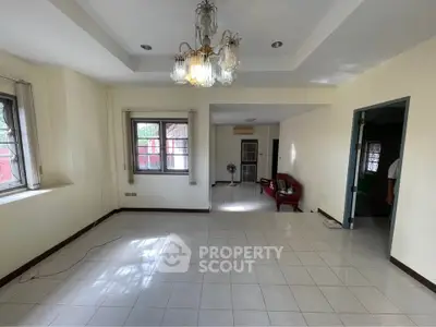 Spacious living room with elegant chandelier and tiled flooring in a bright, airy home.