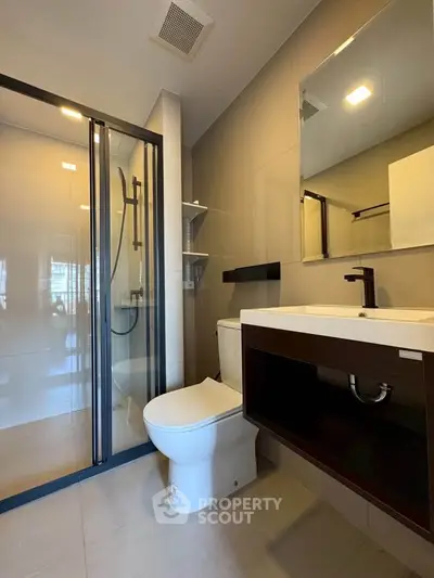 Modern bathroom with glass shower and sleek fixtures in contemporary apartment.