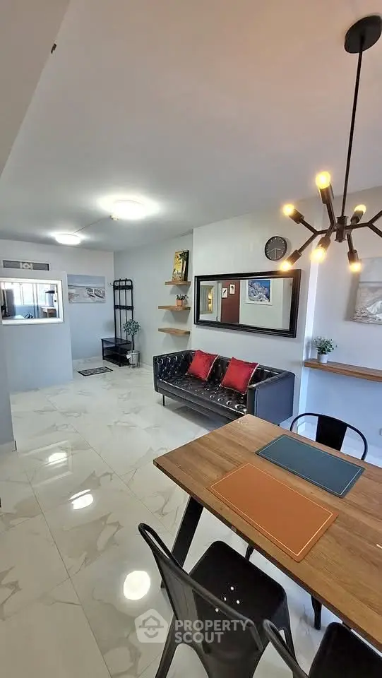 Modern living room with stylish decor and dining area, featuring sleek furniture and contemporary lighting.