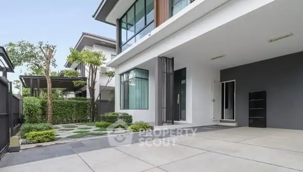 Modern house exterior with spacious driveway and lush greenery.
