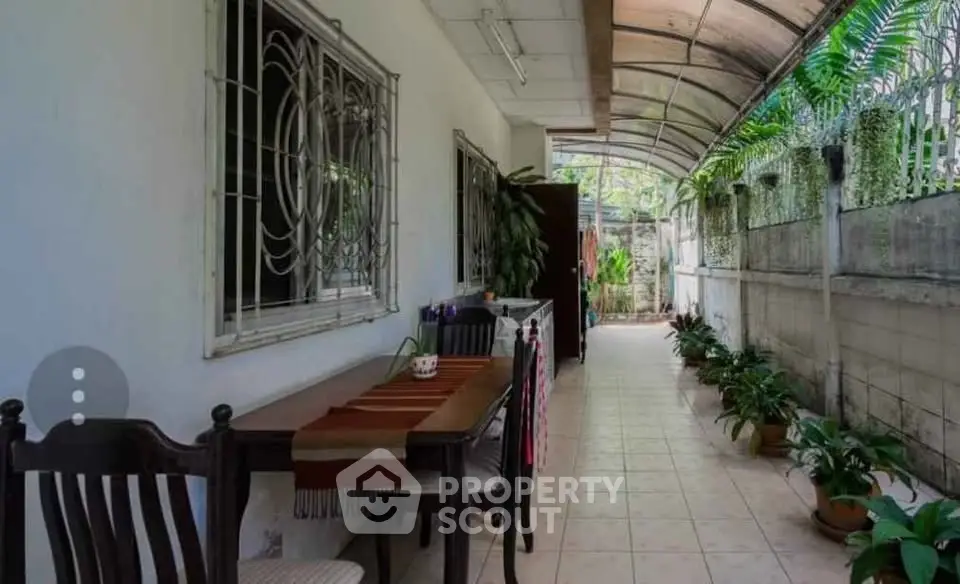 Charming outdoor corridor with dining area and lush greenery, perfect for relaxation and entertaining.