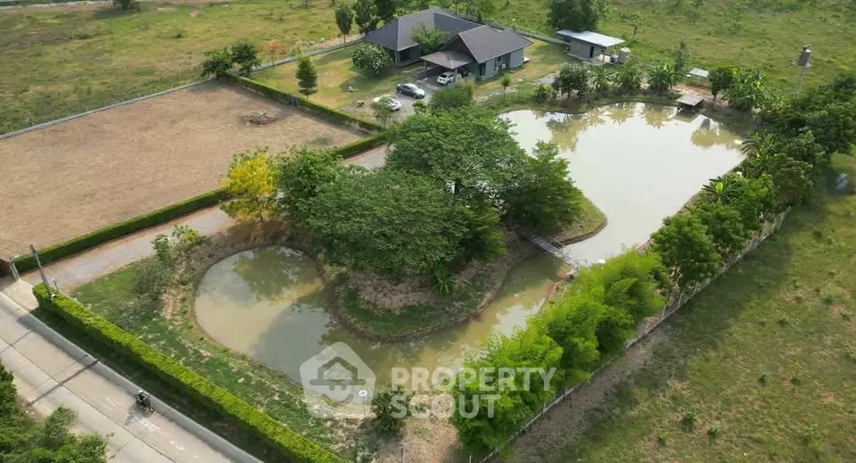 Aerial view of a serene property with a pond and lush greenery, ideal for nature lovers.