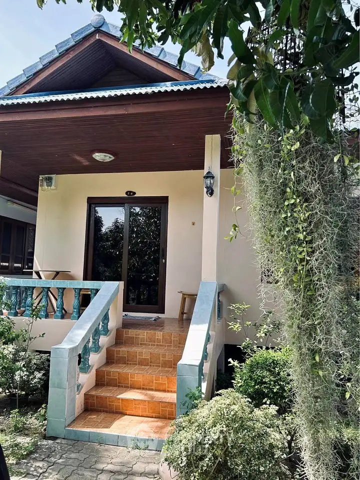 Charming single-story home with inviting front porch and lush garden, perfect for tranquil living.