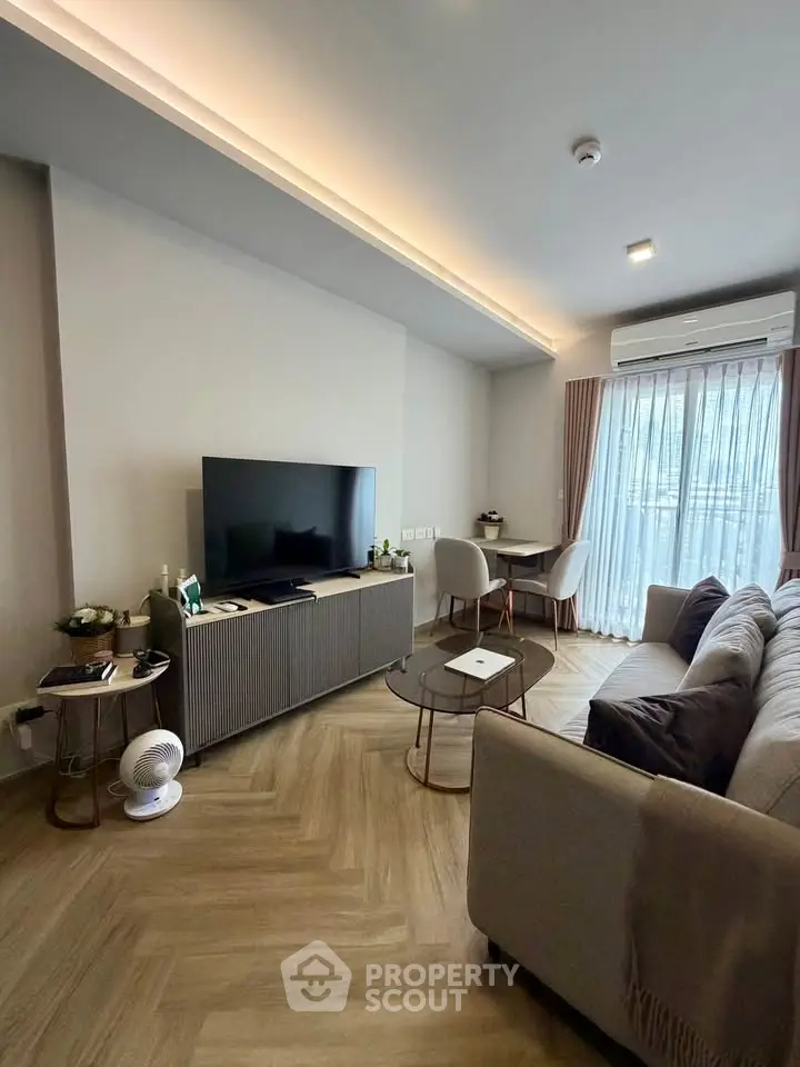 Modern living room with sleek furniture and large TV, featuring elegant lighting and a cozy atmosphere.