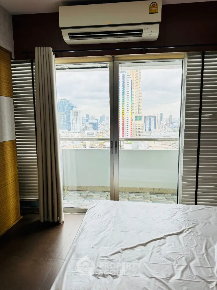 Modern bedroom with balcony offering stunning city skyline view