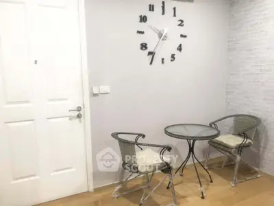 Charming small seating area with modern clock and wicker chairs, perfect for cozy conversations.